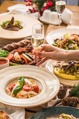 Served table with dishes. side view. light background. hand reaches for a glass of champagne