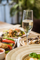 a glass of champagne stands on a served table with dishes.