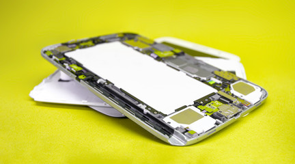 Close-up disassembled mobile phone parts. Tablet repair. Colorful yellow background.