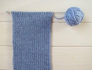 Blue handmade scarf on white wooden background. Hobby-knitting needles. There is room for text. Stock photo.