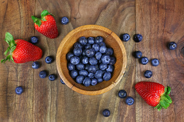 Wooden Bowl of Blueberries with Fresh Strawberries on Rustic Wood Plank Background