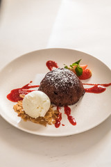 Chocolate fondant on a squirrel plate with strawberries and ice cream.