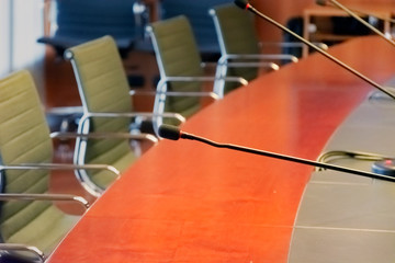 microphone on a wooden table and empty chairs in a boardroom