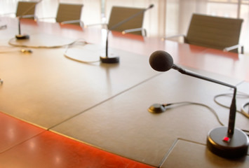 microphone on a wooden table and empty chairs in a boardroom