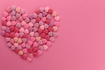 Valentine's day background. Big heart laid out of small hearts on a pink background. Toning pink. Top view, horizontal, close-up, free space on the right.