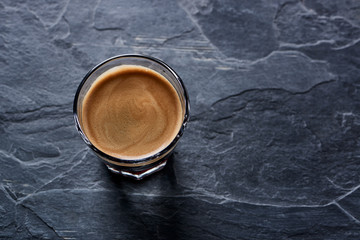 Coffee in glass cup on dark stone background. Copy space. 