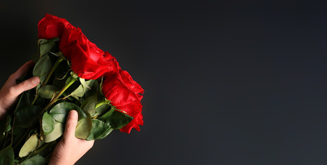 bouquet of red roses in a male hand on a dark background