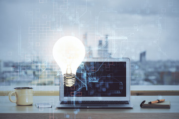 Computer on desktop in office with bulb icon hologram. Multi exposure. Concept of idea.