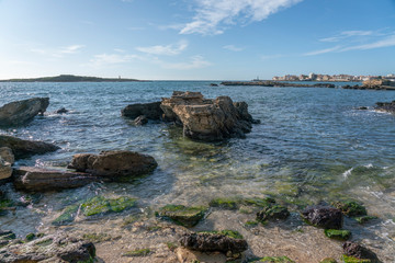 Inspirational rocky landscape in a balearic cove called Can Curt beach, with a centered stone and Colonia de Sant Jordi on the horizon