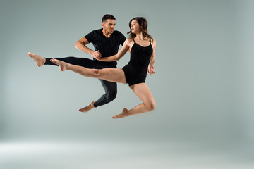 Fototapeta na wymiar handsome and attractive dancers dancing contemporary on grey background