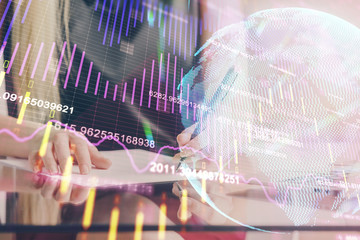 A woman hands writing information about stock market in notepad. Forex chart holograms in front. Concept of research. Double exposure