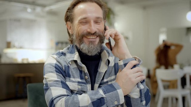 Middle aged man talks on phone in cafe