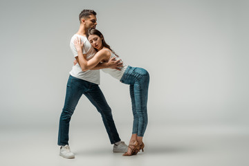 dancers with closed eyes dancing bachata on grey background