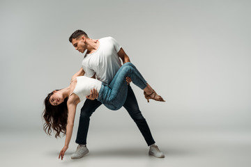 dancers in denim jeans dancing bachata on grey background