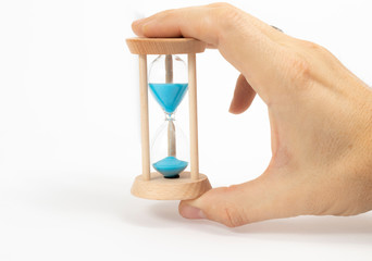 Wooden hourglass in the hands of a man on a white background.  Blue sand, wooden clock.