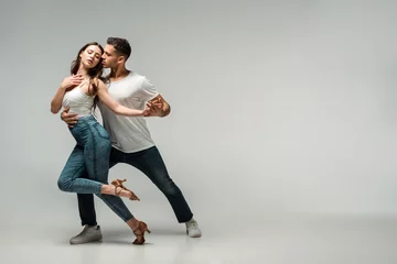 Fotobehang dancers in denim jeans dancing bachata on grey background © LIGHTFIELD STUDIOS