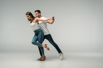 Plakat dancers in denim jeans dancing bachata on grey background