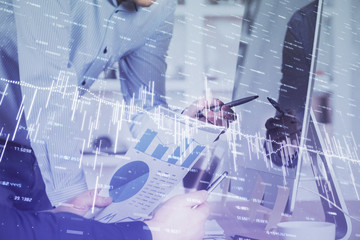 Double exposure of chart with businessman typing on computer in office on background. Concept of hard work.