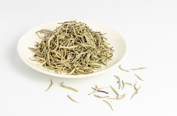 High quality dried white tea leaves in small dish with white background.