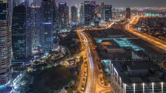 Jumeirah Lake Towers residential district aerial night timelapse near Dubai Marina. Illuminated modern skyscrapers and traffic from above