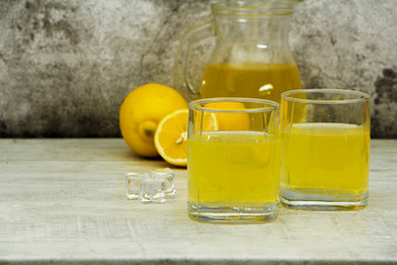 Fresh lemon juice with ice with fresh lemons on a gray background. Lemonade with fresh lemons on a gray background. Fresh juice lemonade.