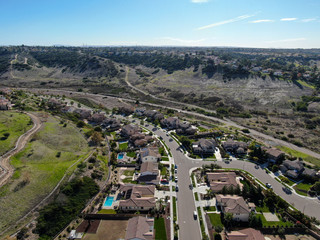 Obraz premium Aerial view of neighborhood with residential modern subdivision luxury houses and small road during sunny day in Chula Vista, California, USA.