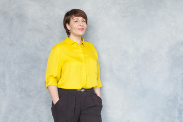 Mature business woman in yellow shirt smiling, portrait