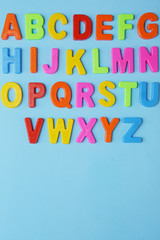 Fun Colored alphabet on a blue background. Back to school concept. Flat lay. Top view. With copy space for text. Vertical photo.