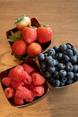 Fresh raspberries , blueberries, strawberry in the copper bowls on rustic natural wooden background