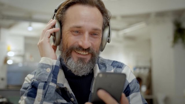Handsome senior man watches video on smartphone