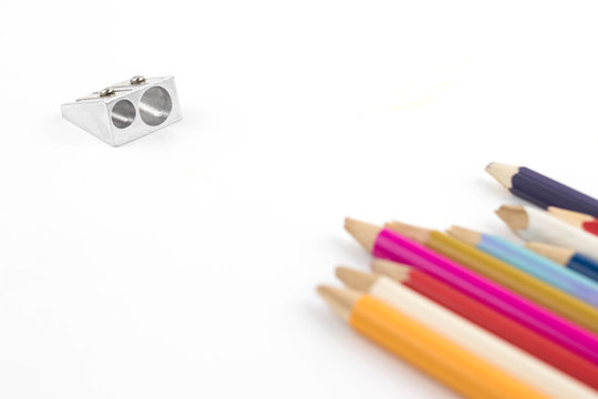 metal pencil sharpener and color broken pencils on a white background. Creativity concept - Powered by Adobe
