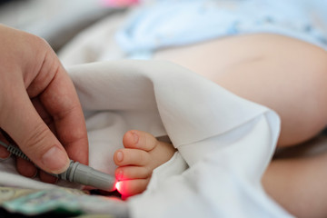 Doctor performs laser therapy on the baby patients toe in rehabilitation centre. Low level laser...