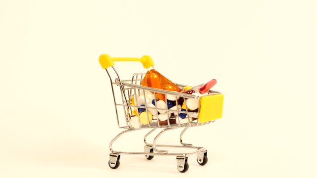 Supermarket trolley filled with medical capsules on a white background