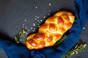 Homemade food concept fresh baked bread braid challah or brioche on black slate stone with copy...