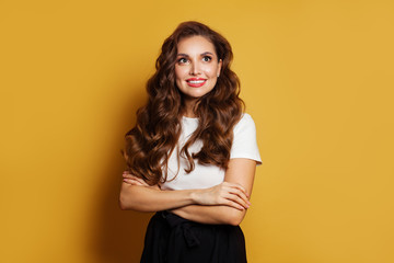 Young woman with crossed arms on bright yellow background