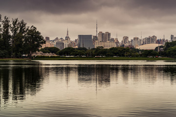 Fototapeta na wymiar Cidade de São Paulo em tarde chuvosa, com reflexo em lago no Parque do Ibirapuera, São Paulo, Brasil