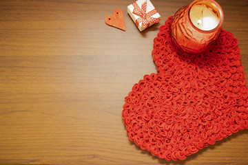 Valentine's Day, February 14th. Red and white heart on a wooden background. With candles and a red silk ribbon.