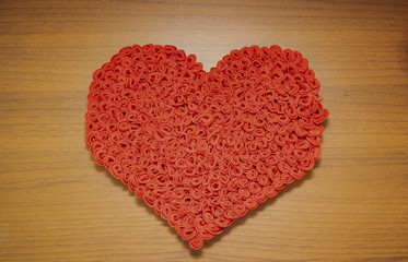 Valentine's Day, February 14th. Red and white heart on a wooden background. With candles and a red silk ribbon.