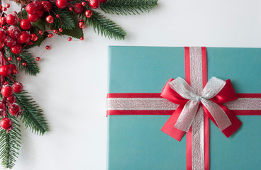 Christmas gift box, berries and cones with copy-space on white paper background.  Holidays...