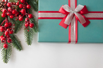 Christmas gift box, berries and cones with copy-space on white paper background.  Holidays...