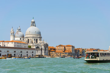Fototapeta na wymiar Bright sunny panorama view of The Grand Canal with gondola and Santa Maria della Salute church, Venice, Italy. Beautiful photo background of the venetian canal.