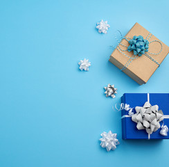 two square gift boxes decorated with ribbons and bows on a blue background