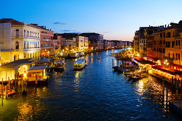 Grand Canal in Venice, Italy at night. View on gondolas and city lights from Rialto Bridge. Beautiful and romantic Italian city on water.