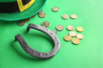 Hat of leprechaun with horseshoe and coins on color background. St. Patrick's Day celebration