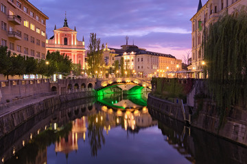 Scenic night lights landscape of the old city. Ljubljanica River with famous Triple Bridge and medieval colorful buildings. Romantic and peaceful scene. Ljubljana, Slovenia