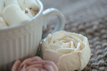 Marshmallow looks like rose close-up. cup with small marshmallows sprinkled with grated chocolate on cotton knitted napkin.