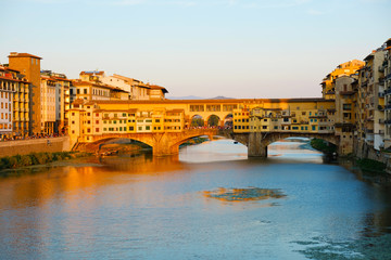 Obraz premium Beautiful landscape view of amazing Florence city with famous medieval stone bridge Ponte Vecchio and the Arno River at sunset light. Firenze scenery panorama, Italy Europe. Italian summer vacation.