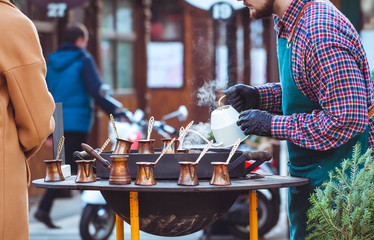 Street coffee shop. Borista is making coffee in Turk on sand.