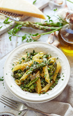 Penne pasta with green asparagus and peas sprinkled with grated Parmesan cheese, top view