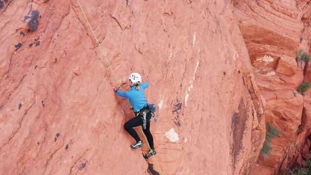 Aerial shot of female rock climber chalking up hands for better grip on rocks